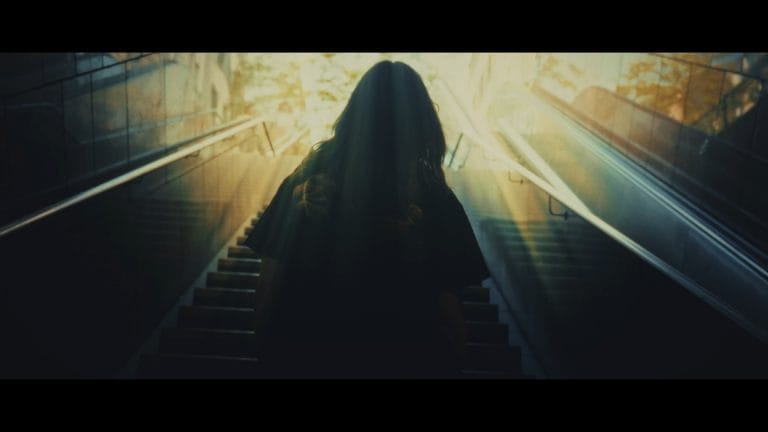 Still des Musikvideo. Cinematisch geht Pia Klein eine Treppe hoch.