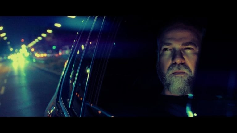 Filmatische Szene aus dem Musikvideo. Wo ein Rapper in einem Wagen sitzt.
