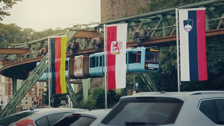 Die Wuppertaler Schwebebahn, wie sie an den Flaggen der Verschiedenen Teams der UEFA 2024 vorbeifährt.